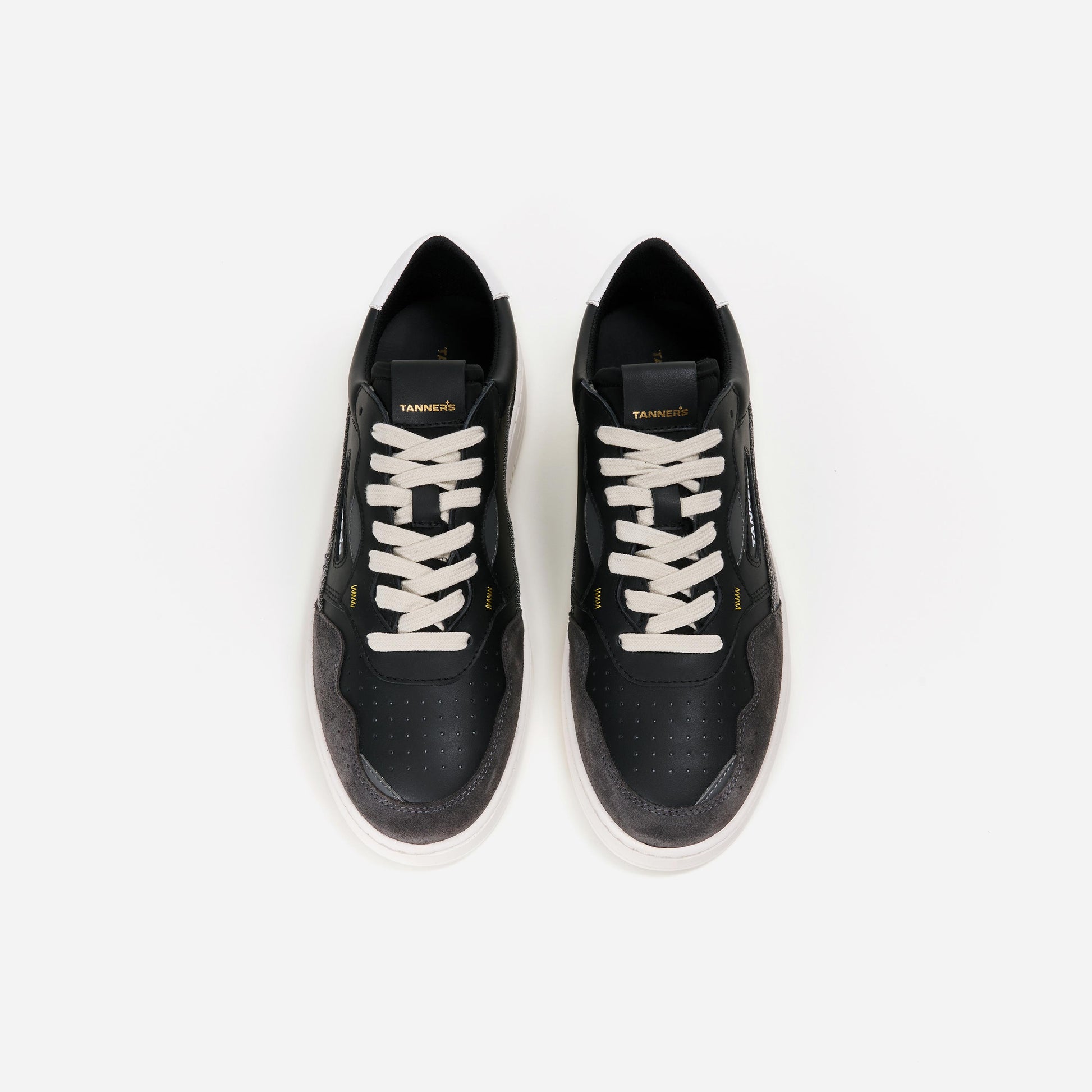 Ein schwarzer Tanners Sneaker, von oben betrachtet. Das Obermaterial ist aus Leder und weist eine glatte Textur auf. Die Schuhsohle hat eine markante Profilstruktur und ist weiß abgesetzt